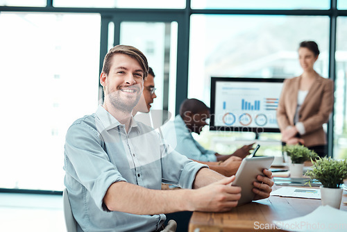 Image of Proud of his career. Portrait of a young businessman using a digital tablet with his colleagues in the background.