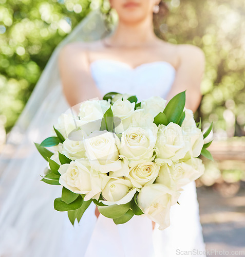 Image of Close up of bride holding a bouquet of flowers while standing outside on a sunny day. Beautiful wedding bouquet of white roses