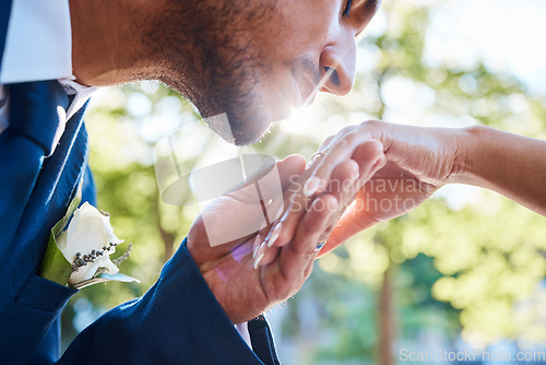 Image of Close up of young handsome charming groom kissing his brides hand while standing outside on a summer day in nature. Gentlemen kissing womans hand after wedding proposal