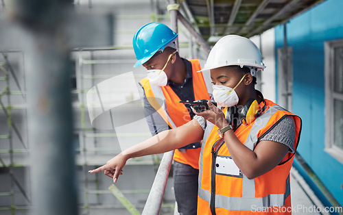 Image of Construction expertise that rises above the rest. a young woman using a walkie talkie while working with her colleague at a construction site.