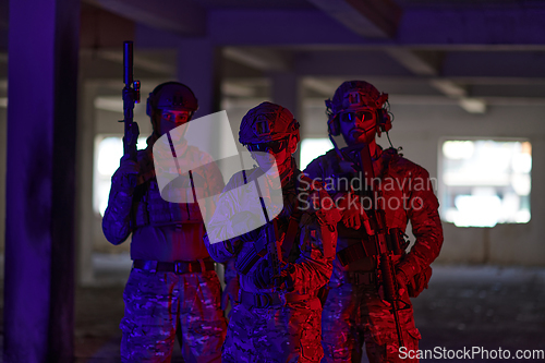 Image of Soldier squad team walking in urban environment colored lightis