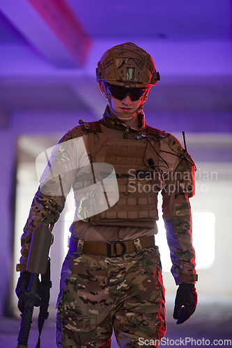 Image of A professional soldier undertakes a perilous mission in an abandoned building illuminated by neon blue and purple lights