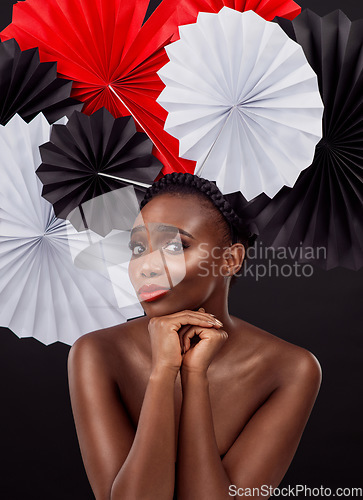 Image of Culture fusion at it’s finest. Studio shot of a beautiful young woman posing with a origami fans against a black background.