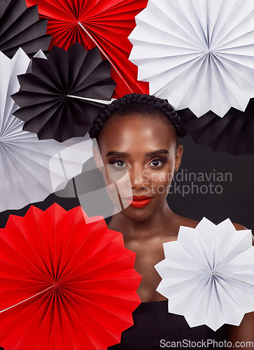 Image of Fashion has the power to connect cultures. Studio shot of a beautiful young woman posing with a origami fans against a black background.