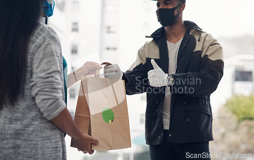 Image of You dont need to go out to get great food. a masked young man showing thumbs up while delivery takeout to a customer at home.