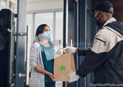 Image of The best and safest in the food delivery business. a masked young woman receiving a takeout delivery at home.