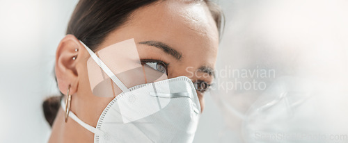 Image of Where do you go when the walls are closing in. a masked young businesswoman looking thoughtfully out of a window in a modern office.