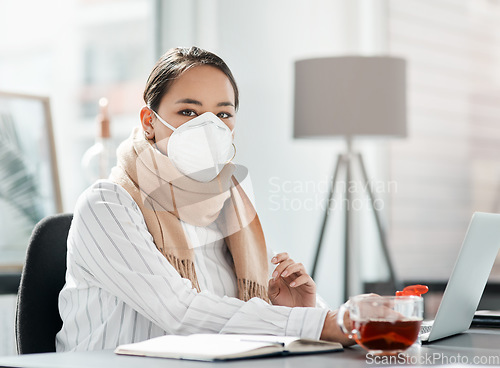 Image of Lets do what we need to do to keep going. a masked young businesswoman using a laptop at her desk in a modern office.