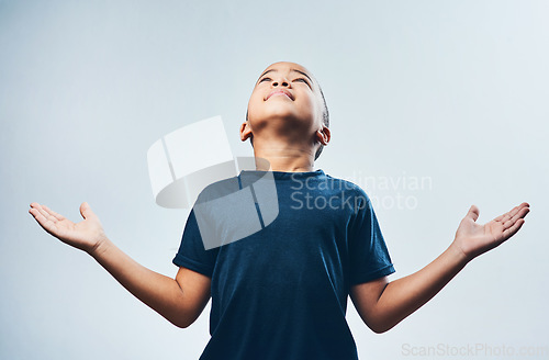 Image of Thank you God for everything. Studio shot of a cute little boy opening his arms and looking up against a grey background.
