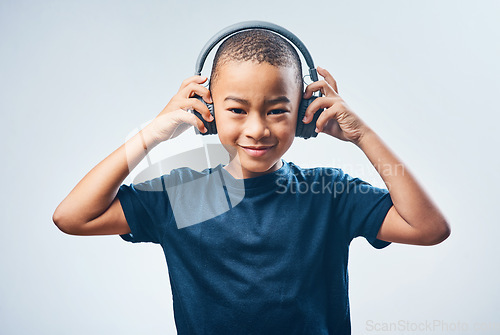 Image of Good sounds make you feel good. Studio shot of a cute little boy using headphones against a grey background.