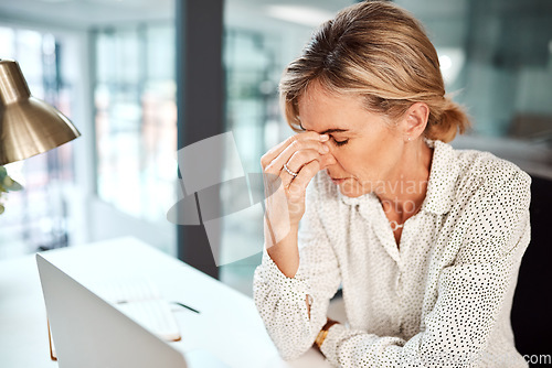 Image of Work anxiety throwing you off balance and leaving you stressed. a mature businesswoman looking stressed out while working in an office.