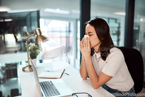 Image of Her sinuses are kicking in. a young businesswoman blowing her nose while working in an office.