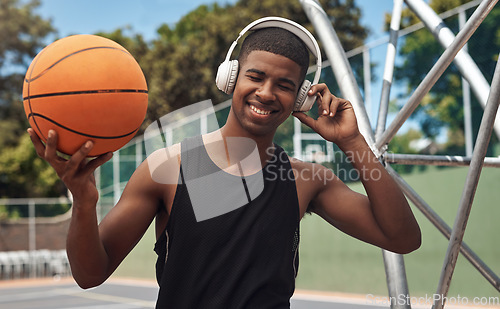 Image of Playing basketball automatically makes you cool. a sporty young man listening to music while playing basketball on a sports court.