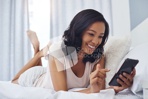 Image of Taking her social media roll call. a young woman waking up in the morning and using her phone in bed.