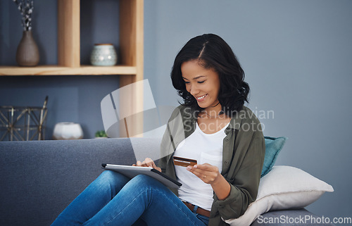 Image of When your saving finally paid off. an attractive young woman using a digital tablet and credit card on the sofa at home.