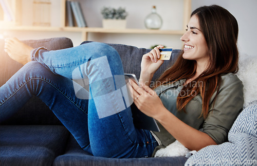 Image of I cant wait for it to be delivered. a young doing online shopping while relaxing on her couch at home.