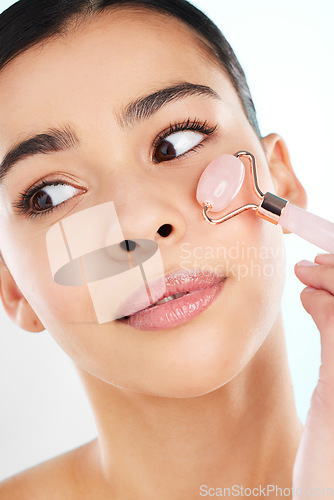 Image of Rolling away those wrinkles. Studio shot of an attractive young woman using a face massager against a light background.