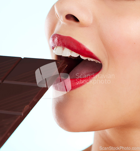 Image of Something sweet. Studio shot of an unrecognizable young woman biting into a slab of chocolate against a light background.