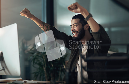 Image of Shift work can be rewarding work. a young businessman cheering while using a computer during a late night at work.