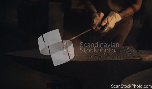 Image of Even the strongest steel can sometimes bend. a blacksmith working with a hot metal rod in a foundry.
