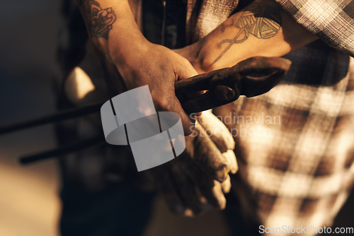 Image of A blacksmiths hands are her greatest tools. an unrecognisable holding a pair of gloves while working at a foundry.