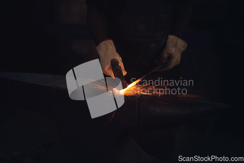 Image of It might be steel but its worth more than gold. a blacksmith hitting a hot metal rod with a hammer in a foundry.
