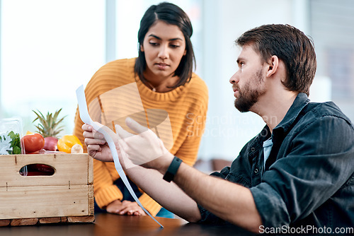 Image of Unhealthy financial choices can make an unhealthy marriage. a young couple going through their receipts at home after buying groceries.