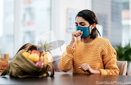 Image of Not just groceries you could bring back from the store. a masked young woman coughing after returning home from buying groceries.