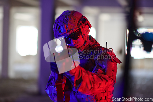 Image of A professional soldier undertakes a perilous mission in an abandoned building illuminated by neon blue and purple lights