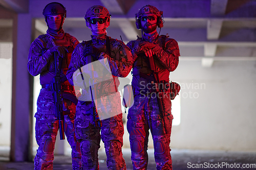 Image of Soldier squad team walking in urban environment colored lightis