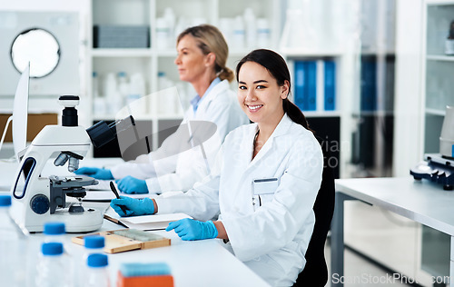Image of Science really holds so many answers about the world. Portrait of a young scientist working in a lab with her colleague in the background.