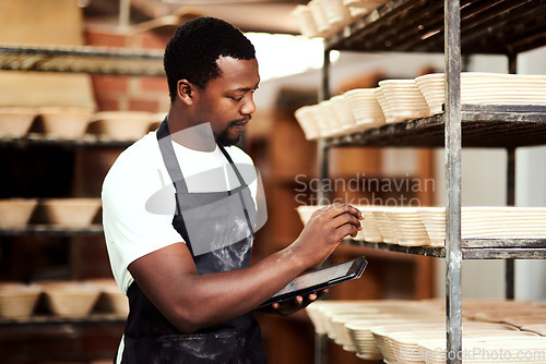 Image of I found a great tool to help me keep track of orders. a man using a digital tablet while working in a bakery.