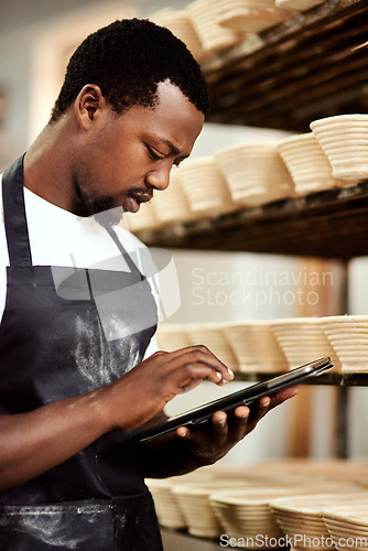 Image of Freshness is my promise to all my customers. a man using a digital tablet while working in a bakery.