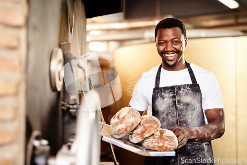 Image of Now all you need is some butter. a male baker holding up freshly baked bread in his bakery.