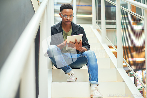 Image of Whatever the task, technology will handle it. a young businessman using a digital tablet on the stairs of a modern office.