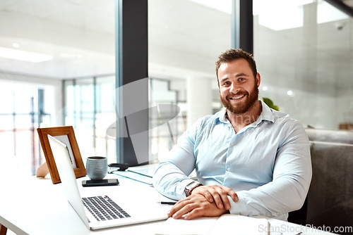 Image of Im happy with how far Ive come in my career. Portrait of a young businessman sitting at a desk in an office.