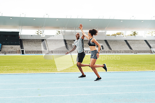 Image of Yes We finished. Full length shot of two young athletes giving each other a high five during a run on a track field.