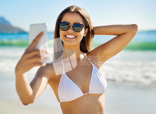 Image of This selfie is gonna be so hot. a beautiful young woman taking a selfie at the beach.