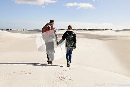 Image of Sharing the wild places together. a happy couple hiking in the dunes together.