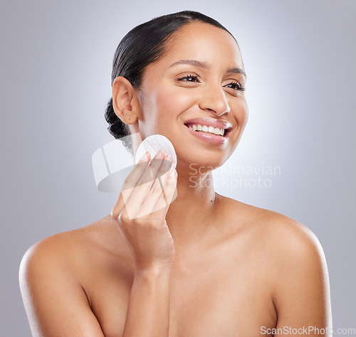 Image of A good skincare routine is vital. an attractive young woman standing alone in the studio and using a cotton pad on her face.