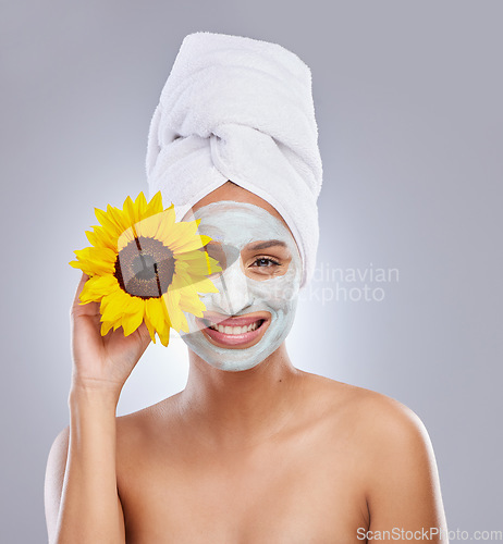 Image of Skincare routines make me happy. an attractive young woman wearing a face mask and holding a sunflower over her eye in the studio.