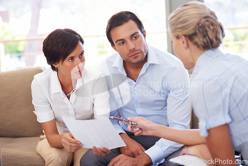 Image of Laying out different investment options. a financial advisor explaining documents to a couple.