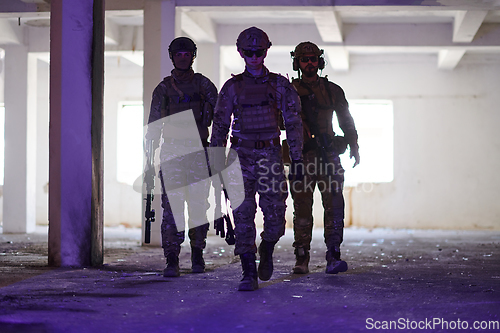 Image of Soldier squad team walking in urban environment colored lightis