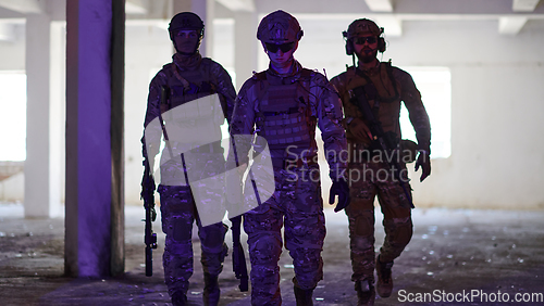 Image of Soldier squad team walking in urban environment colored lightis