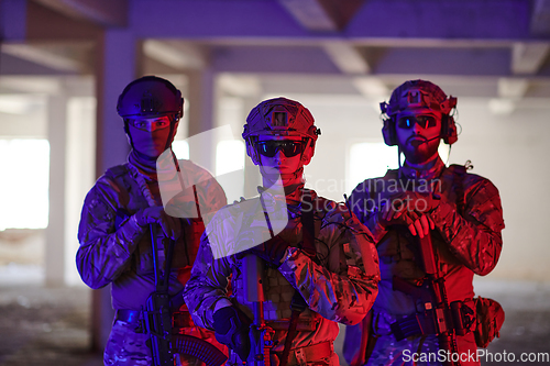 Image of Soldier squad team walking in urban environment colored lightis