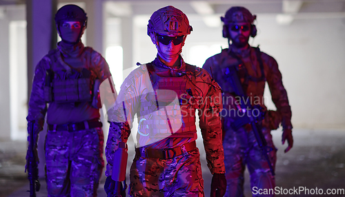 Image of Soldier squad team walking in urban environment colored lightis