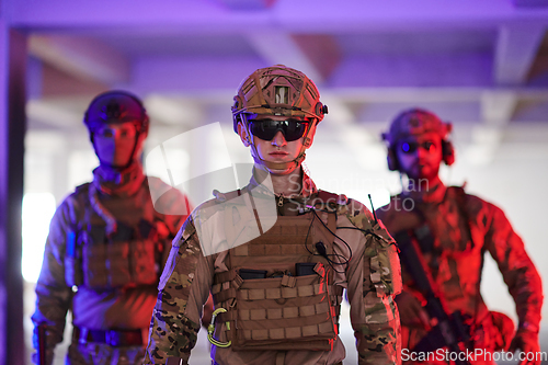 Image of Soldier squad team walking in urban environment colored lightis