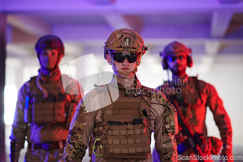 Image of Soldier squad team walking in urban environment colored lightis