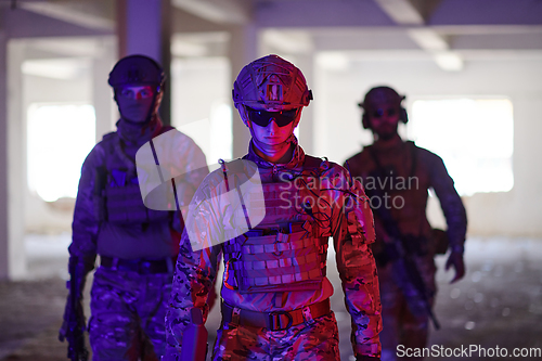 Image of Soldier squad team walking in urban environment colored lightis