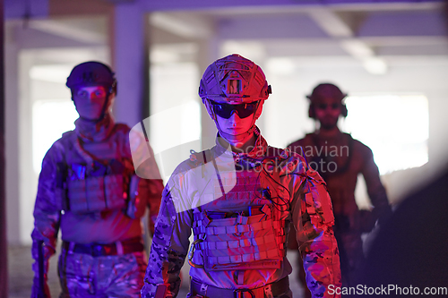 Image of Soldier squad team walking in urban environment colored lightis